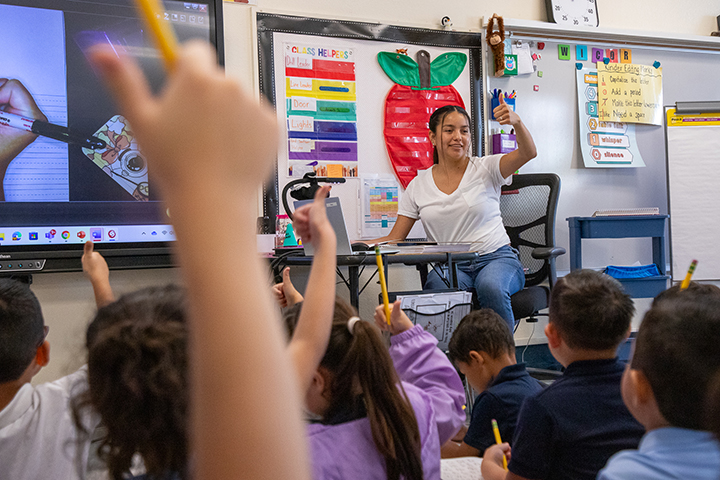 Students raise their thumbs during class