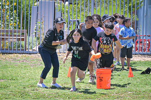 Students stand in a line, getting ready to run across the field holding a wet sponge